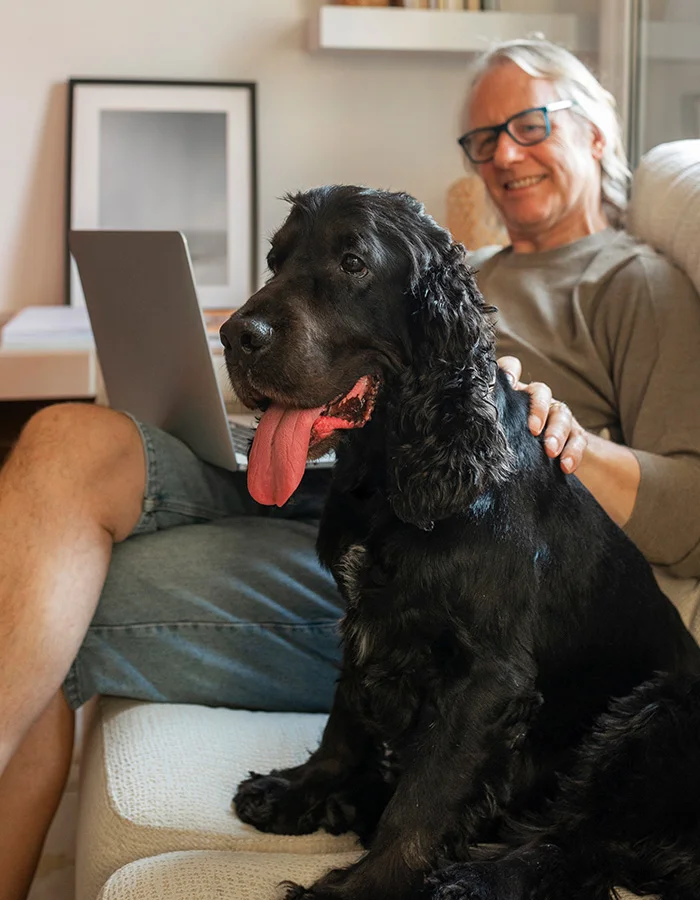 black-dog-sits-by-owner A black dog sits beside its owner while the owner works on his computer