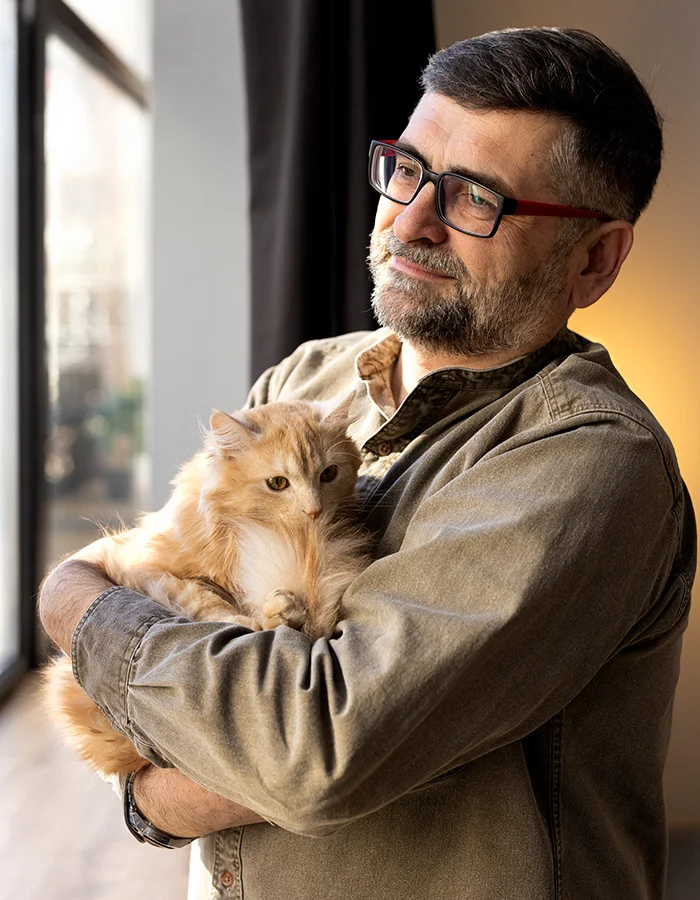 man-holding-elderly-cat A man holds his elderly cat while looking out a window