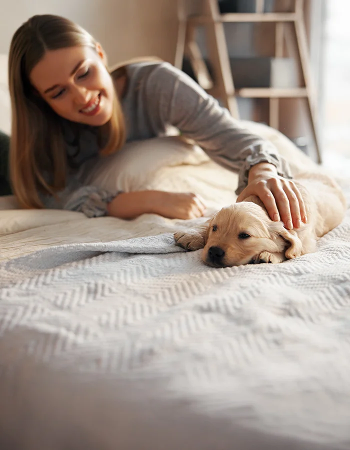 puppy-with-owner-on-bed A woman and her puppy lay on a bed together